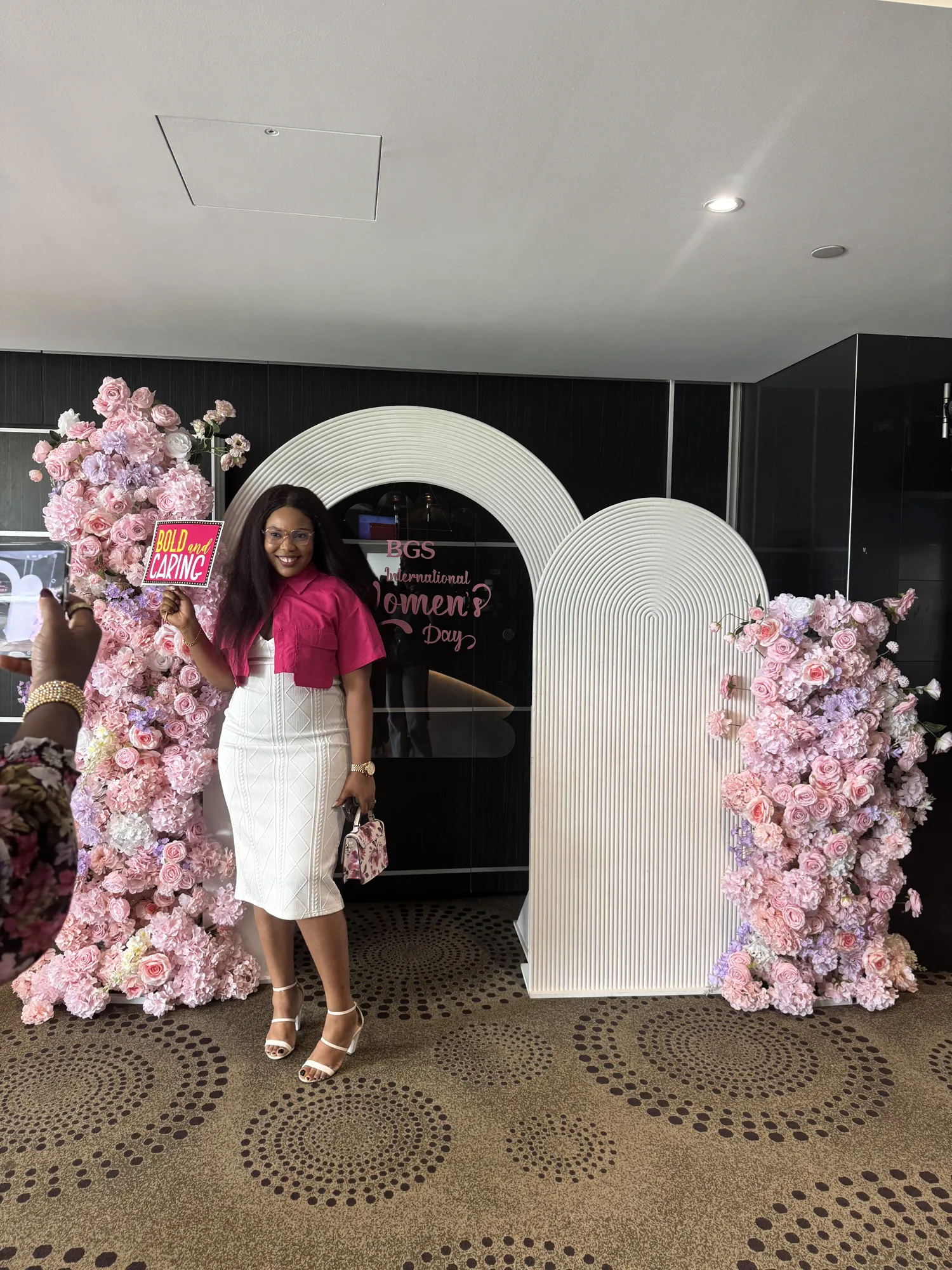 A closer view of a pink floral arch and a neon sign reading International Women's Day.