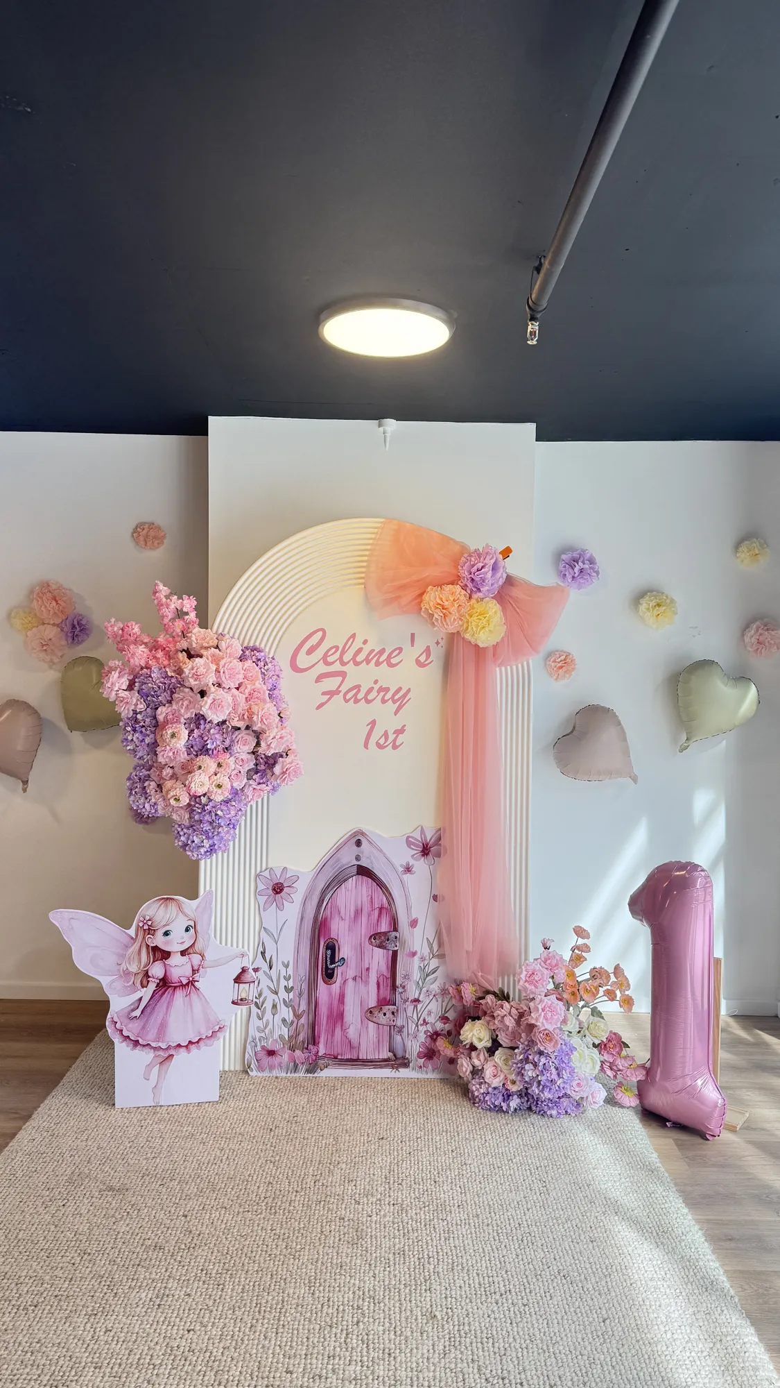 A place setting with a pink napkin, gold cutlery, and a butterfly decoration, with fairy wings and a marquee 1 behind.