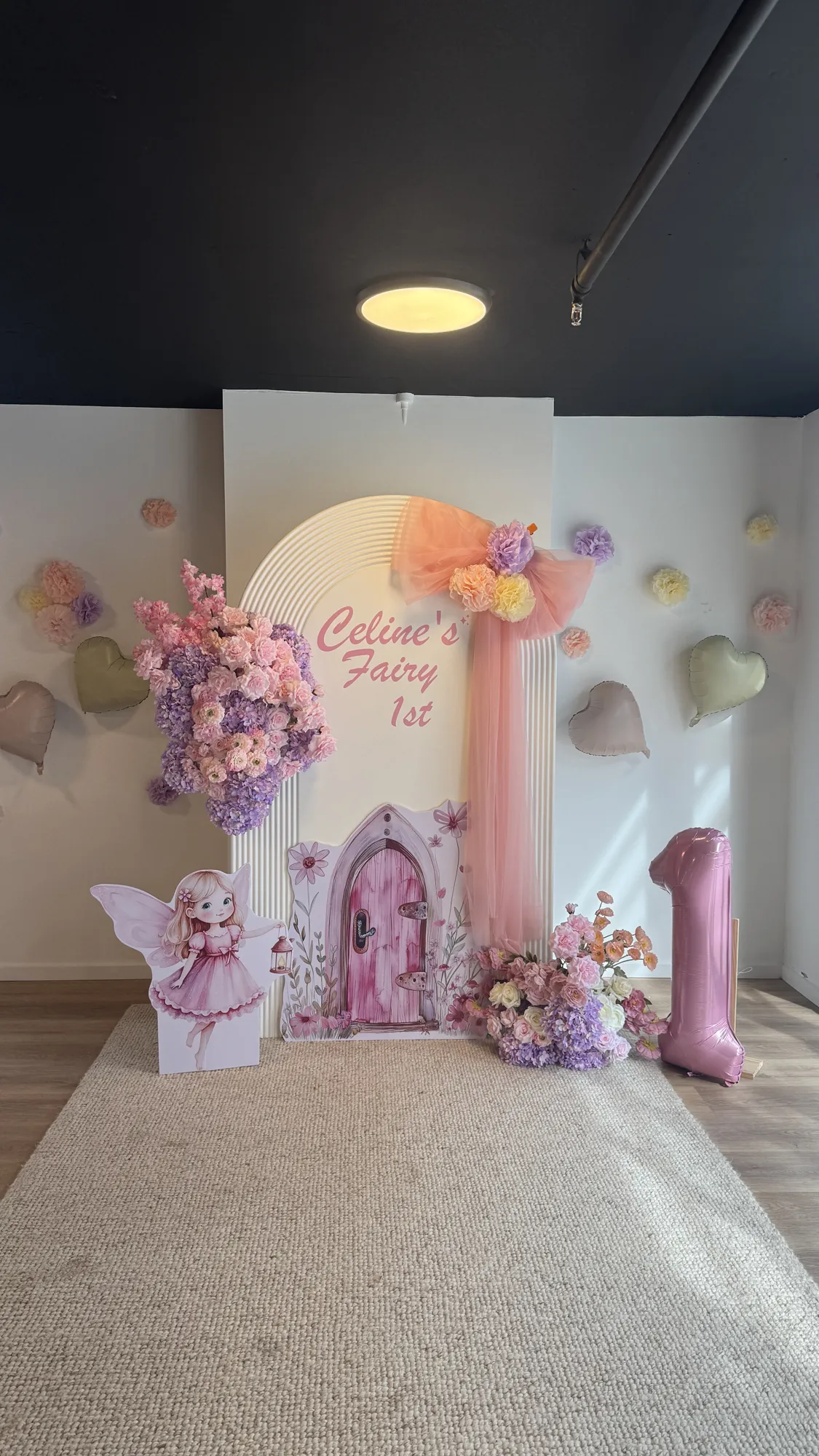A place setting with a pink napkin and gold cutlery, with a butterfly cake and a marquee 1 behind.
