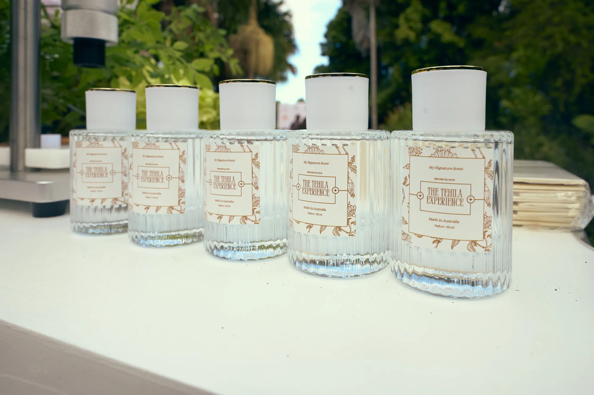 Three signature scent bottles on gold trays, with testers and scent cards on a white table.