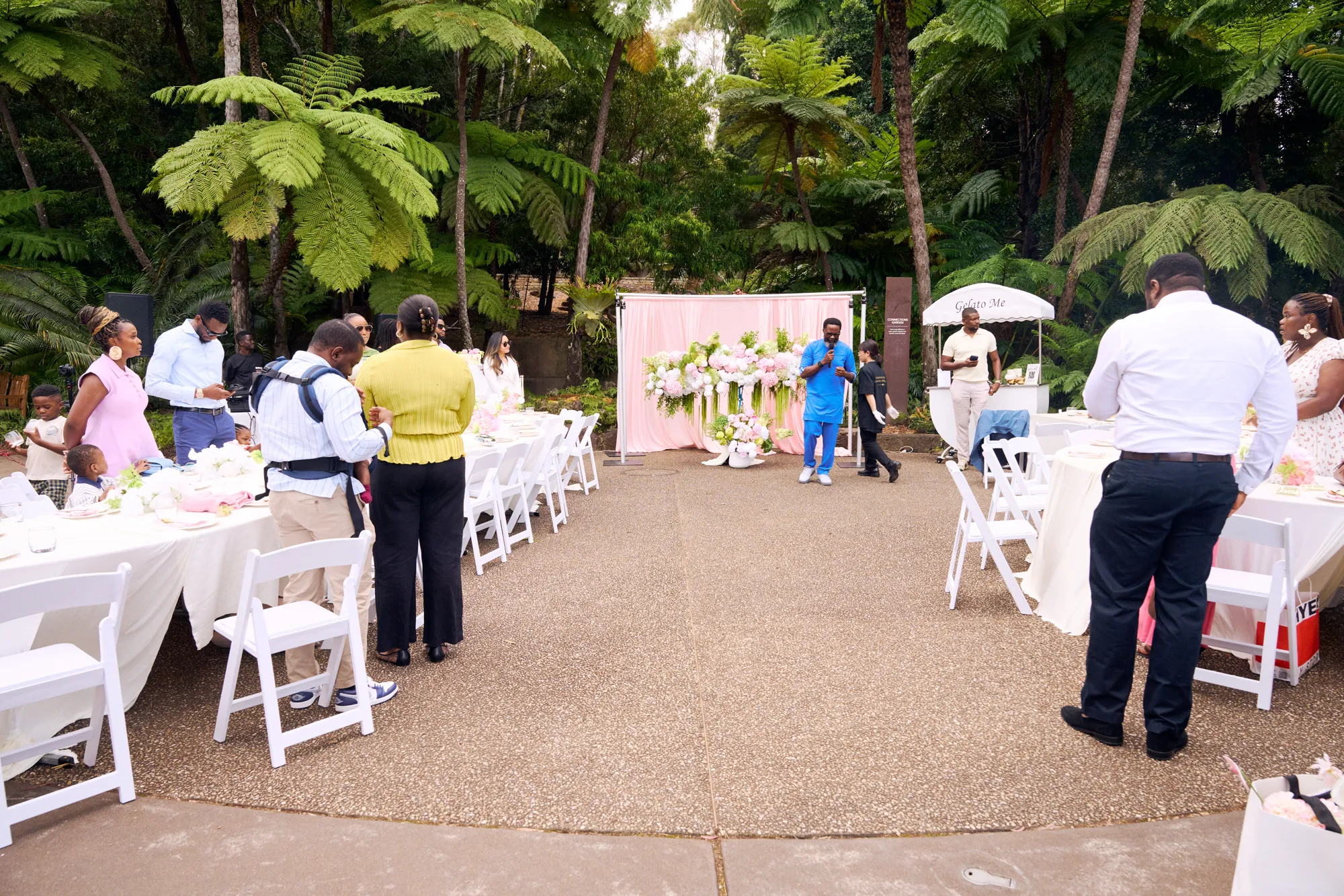 A wide view of round tables in gold and white under chandeliers at The Tehila Experience, Mount Annan.